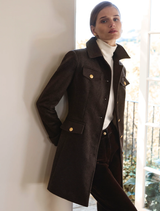 Model wearing the Delta Jacket - Chocolate with gold buttons over a white turtleneck