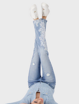 A woman wearing stylish jeans adorned with lace accents, showcasing a modern and fashionable look against a simple backdrop.