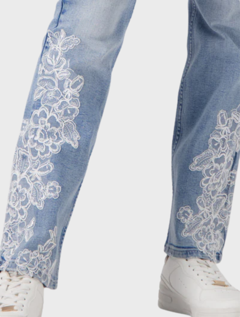 A woman sporting jeans with delicate lace details, presenting a trendy outfit choice in a minimalistic environment.