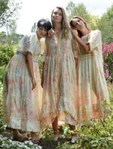 A three woman in a vintage floral dress meanders through a garden, enjoying the beauty of the blooming flowers.