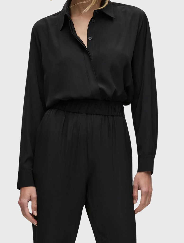The model is dressed in a sleek black jumpsuit complemented by a button-down shirt.
