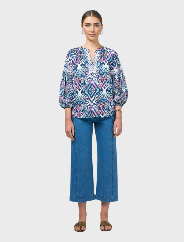 A model showcases a blue and white printed blouse, featuring a stylish design and elegant fit.