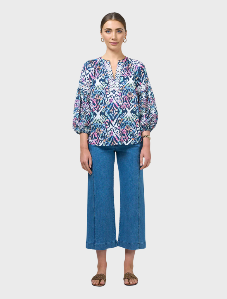 A model showcases a blue and white printed blouse, featuring a stylish design and elegant fit.