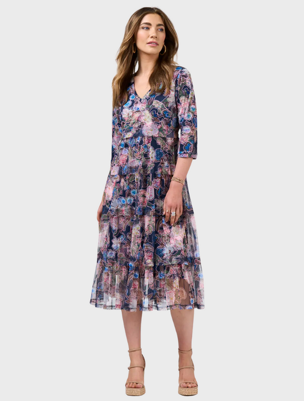 A woman wearing a floral dress, standing outdoors.