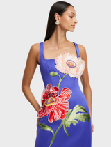 A woman is wearing a blue day dress adorned with a floral design.