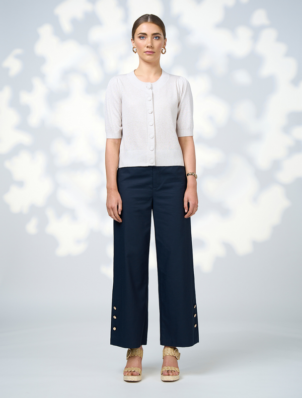  A model showcases navy wide-leg pants featuring decorative buttons along the front.