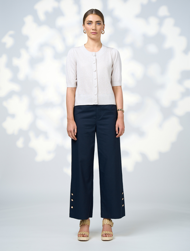  A model showcases navy wide-leg pants featuring decorative buttons along the front.