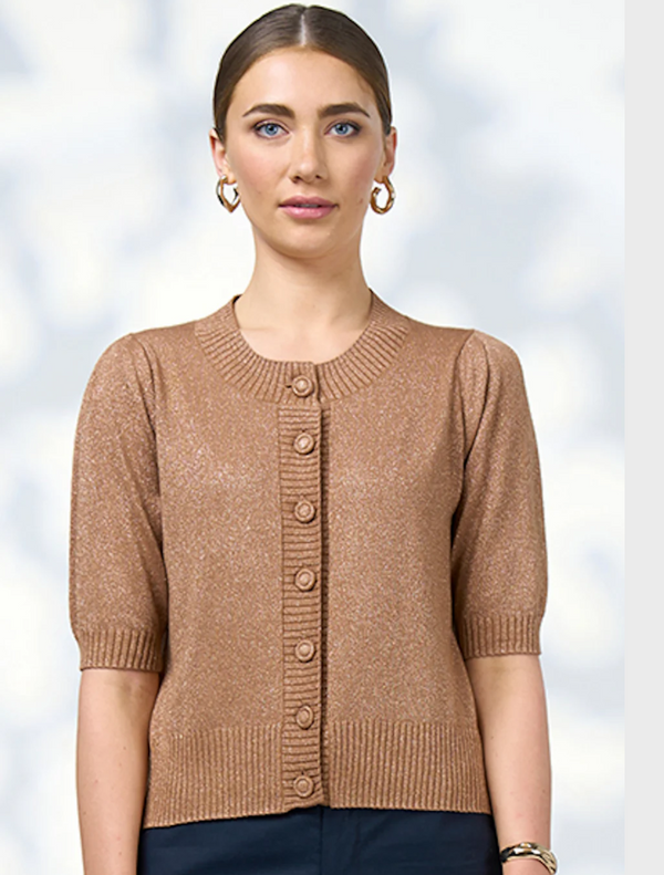 A woman wearing a brown cardigan sweater, standing confidently with a neutral background.