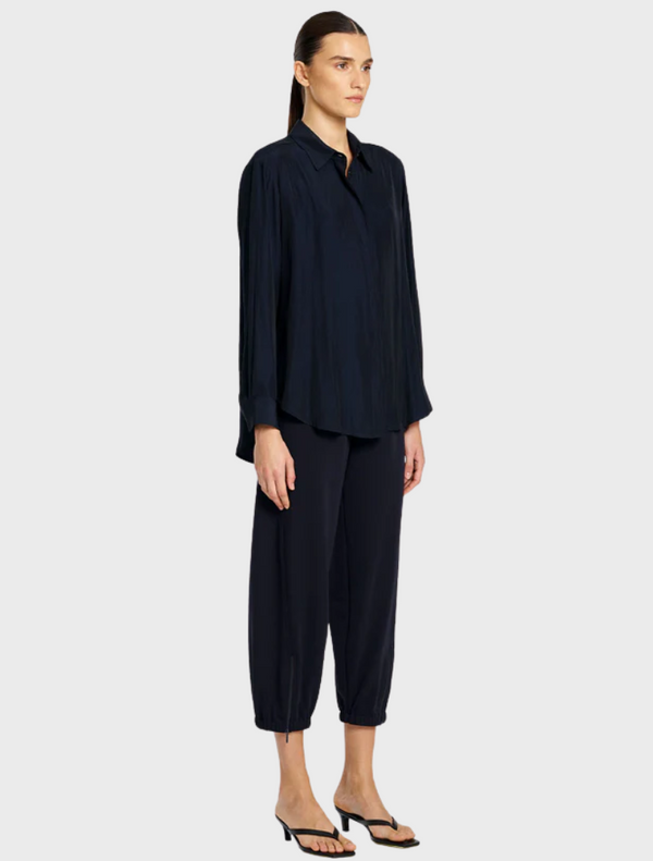 The model showcases a navy shirt paired with navy pants, presenting a sleek and modern fashion look.