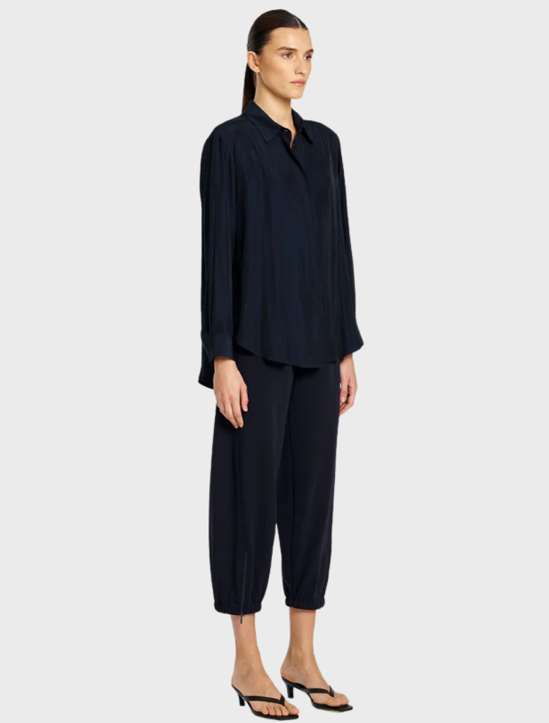 The model showcases a navy shirt paired with navy pants, presenting a sleek and modern fashion look.