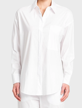 White relaxed pocket shirt displayed on a hanger, featuring a simple design and casual style.
