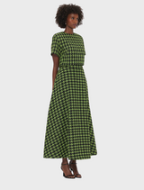 A model showcases a stylish, Rosalyn Tweed Maxi Skirt with a green and black houndstooth pattern, featuring a fitted waist.