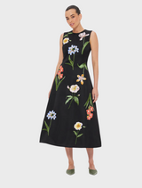 A woman wearing a black dress adorned with floral patterns.