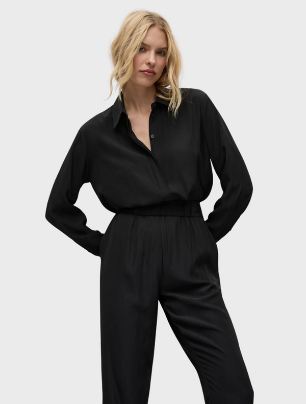 A model showcases a black jumpsuit paired with a stylish button-down shirt.