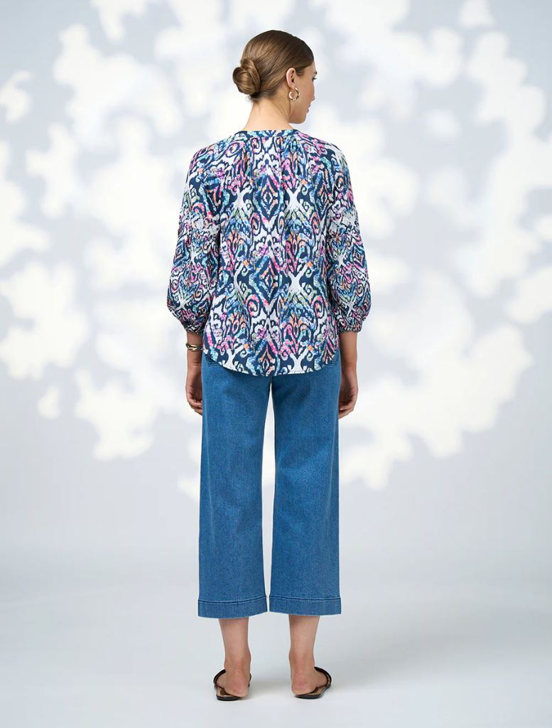 A model displays a blue and white printed blouse, emphasizing its modern design and fashionable appeal.