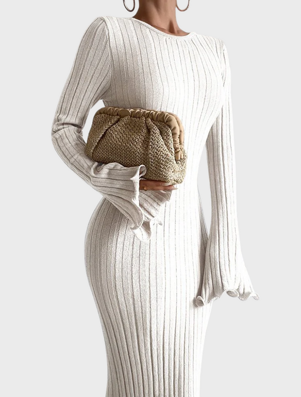 A woman in a white dress holds a natural-colored Amalia pleated woven clutch with a gold accent.
