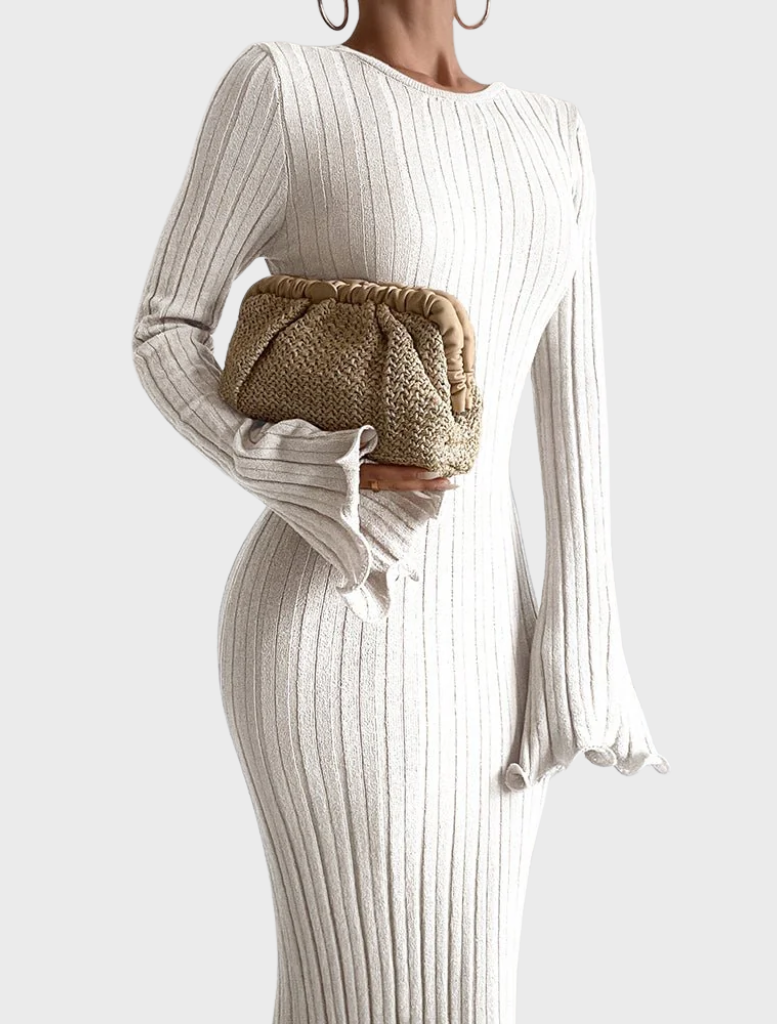 A woman in a white dress holds a natural-colored Amalia pleated woven clutch with a gold accent.