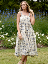 A model poses in a blue and white floral print dress, showcasing its vibrant design and elegant silhouette.