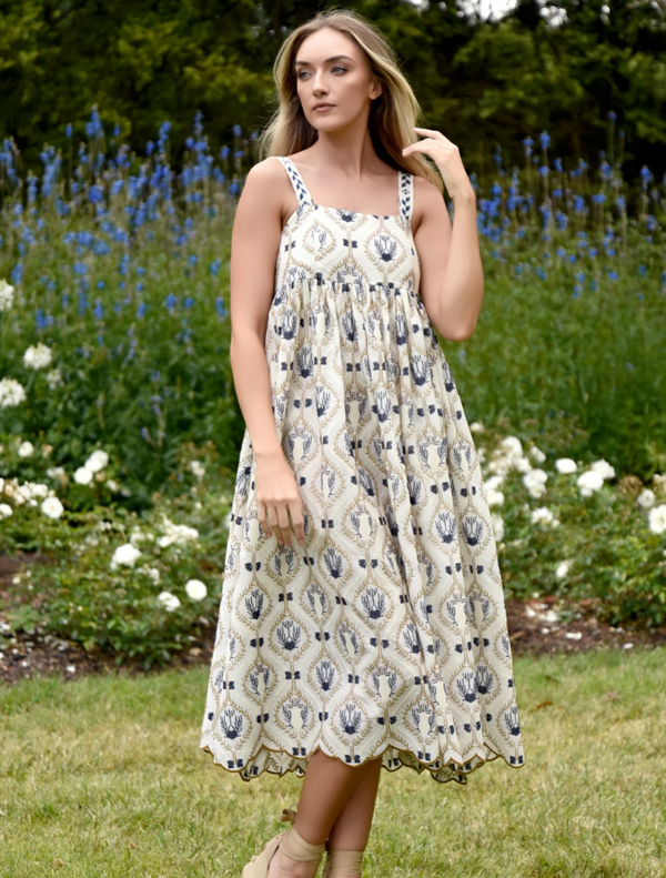 A model poses in a blue and white floral print dress, showcasing its vibrant design and elegant silhouette.