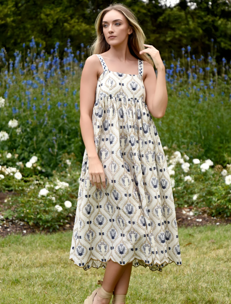 A model poses in a blue and white floral print dress, showcasing its vibrant design and elegant silhouette.
