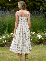 A model is dressed in a blue and white floral print dress, featuring a charming design and graceful flow.