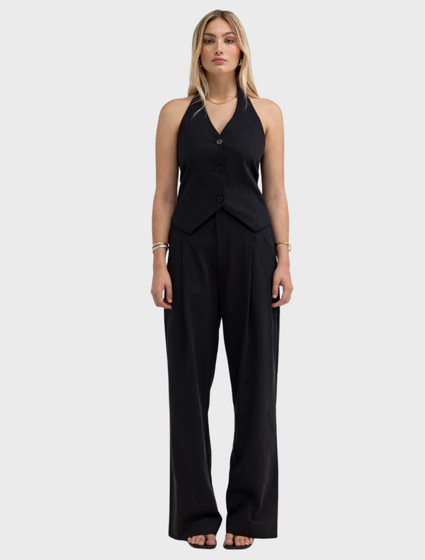 Model in a black v-neck jumpsuit featuring wide leg pants, showcasing a stylish and modern silhouette.