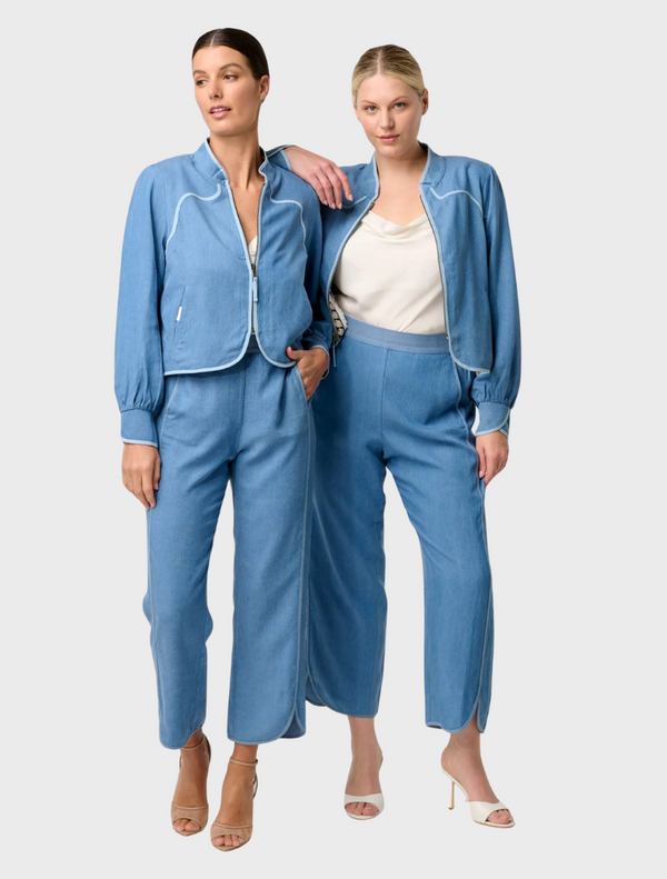 Two women wearing floral jackets and skirts, featuring the Aurora Reversible Viscose & Tencel Fringe Jacket in blue ash.
