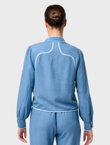 Back view of a woman in a blue denim jumpsuit, showcasing the Aurora Reversible Viscose & Tencel Fringe Jacket.