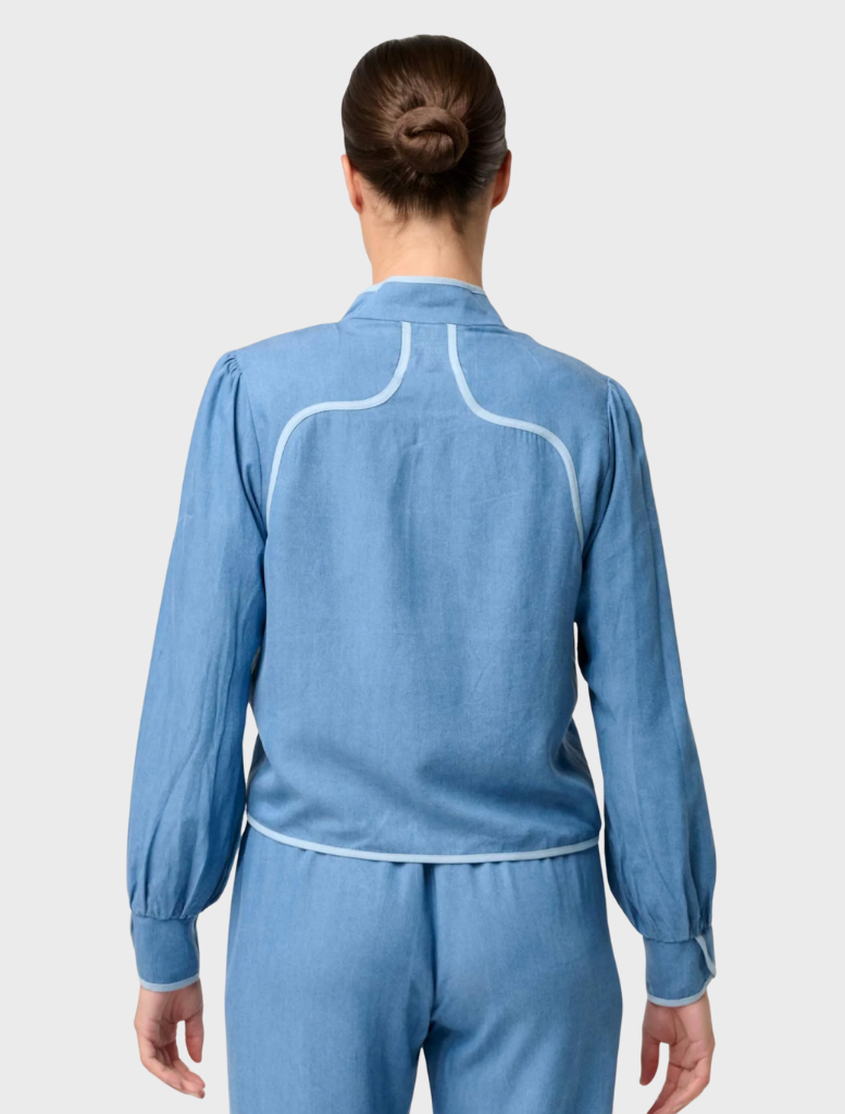 Back view of a woman in a blue denim jumpsuit, showcasing the Aurora Reversible Viscose & Tencel Fringe Jacket.