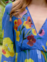A woman models a cobalt floral dress, showcasing its vibrant blue pattern and elegant design.