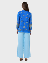 Azure multi blouse with blouson sleeves, elastic cuffs, ruffles on front and back, and a glass bead tie at the neckline.