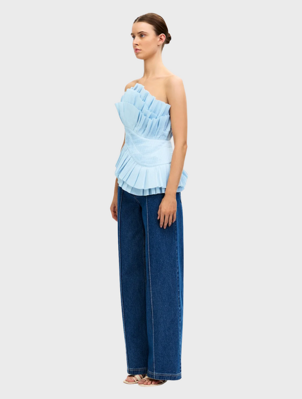 Light blue Tremail top hanging, showcasing a minimalist style and soft fabric ideal for everyday outfits.