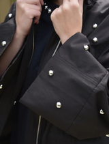 Front view of a black Baby I'm Back Jacket, highlighting its modern cut and sleek appearance.