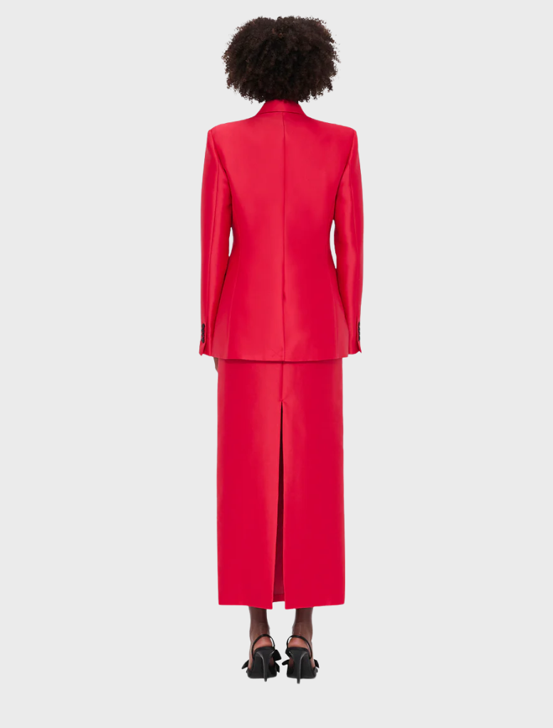 Back view of a woman in a tailored red suit, showcasing a professional and stylish appearance.