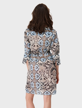 Back view of a woman in a blue and white print dress, showcasing the design and flow of the fabric.