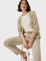 A woman in beige pants and a white top stands, representing a modern and casual style.