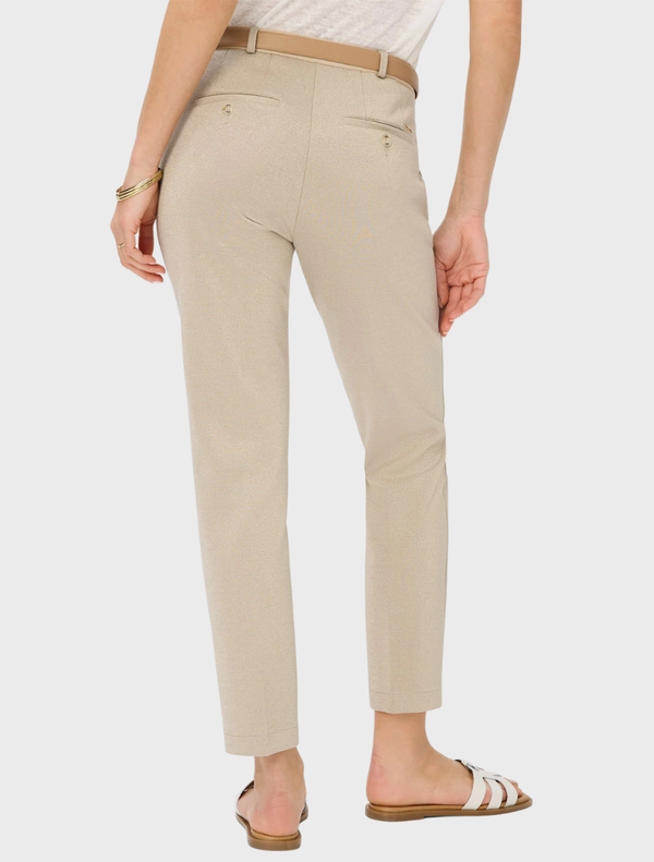 A woman dressed in beige pants and a white shirt poses, highlighting a simple and elegant fashion choice.