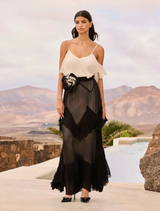 Black and white maxi dress with ruffle detailing, pointed cutouts, and a removable tie-dye flower belt for a sophisticated look.