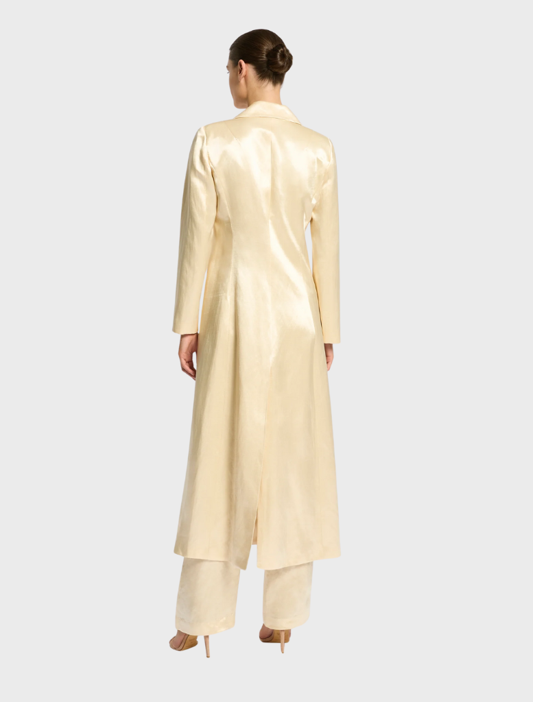 A close-up of a buttermilk trench coat, highlighting its fabric texture and tailored details.