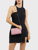 A woman wearing a black dress carries a pink Birdie Textural Handle Bag, adding a pop of color to her elegant look.