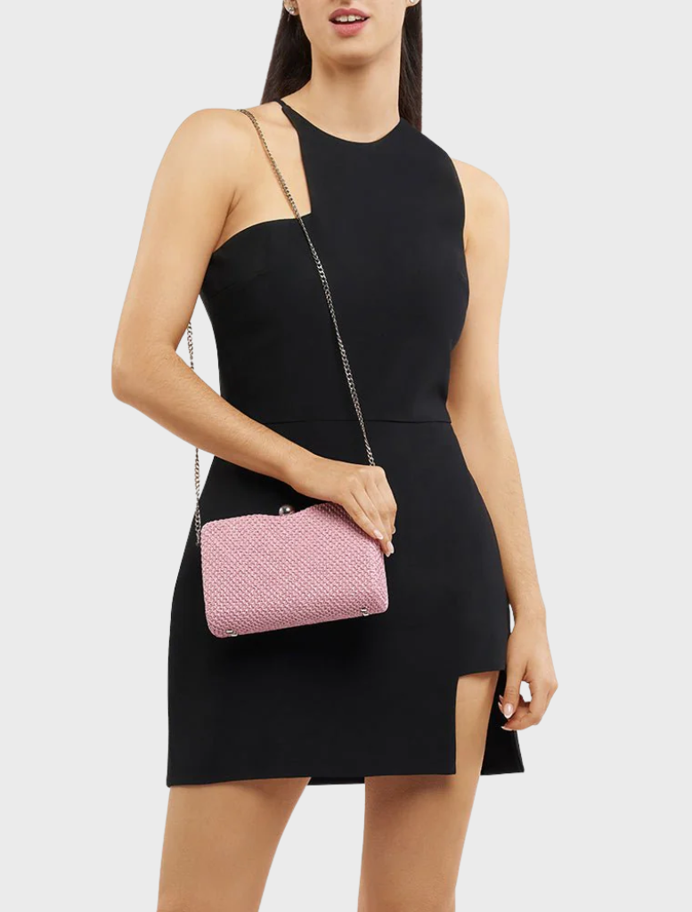 A woman wearing a black dress carries a pink Birdie Textural Handle Bag, adding a pop of color to her elegant look.