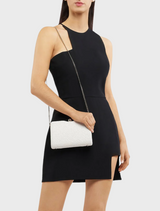 A woman wearing a black dress carries a white Birdie Textural Handle Bag, highlighting her elegant fashion choice.