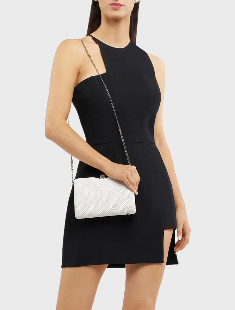 A woman wearing a black dress carries a white Birdie Textural Handle Bag, highlighting her elegant fashion choice.