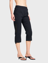 A woman dressed in black shorts and a cropped zip cargo top, showcasing a casual yet stylish outfit.