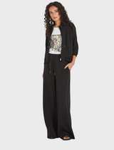 The image features a model dressed in black pants paired with a white top, highlighting a chic fashion choice.