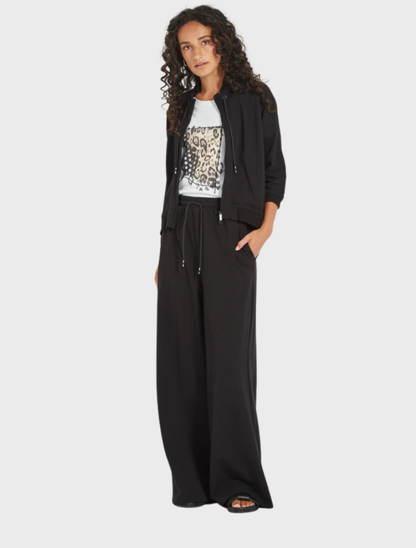 The image features a model dressed in black pants paired with a white top, highlighting a chic fashion choice.