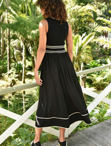 A woman wearing a black dress and sneakers stands for a photo, blending elegance with a sporty vibe.