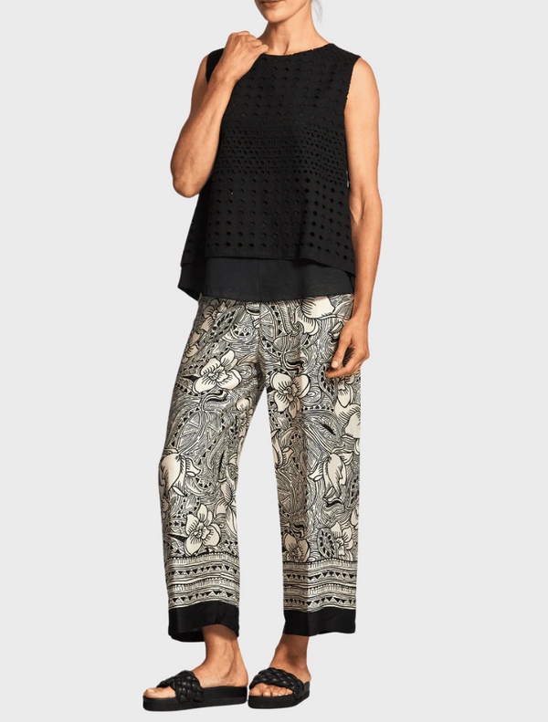 A woman is dressed in floral print pants, featuring a colorful and trendy pattern.
