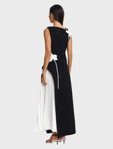 Modern black and ivory maxi dress with a pleated side skirt and textured flower details, suitable for evening gatherings.