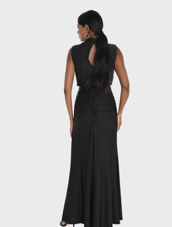 Elegant black dress adorned with white polka dots, showcasing a classic silhouette, hanging against a light backdrop.